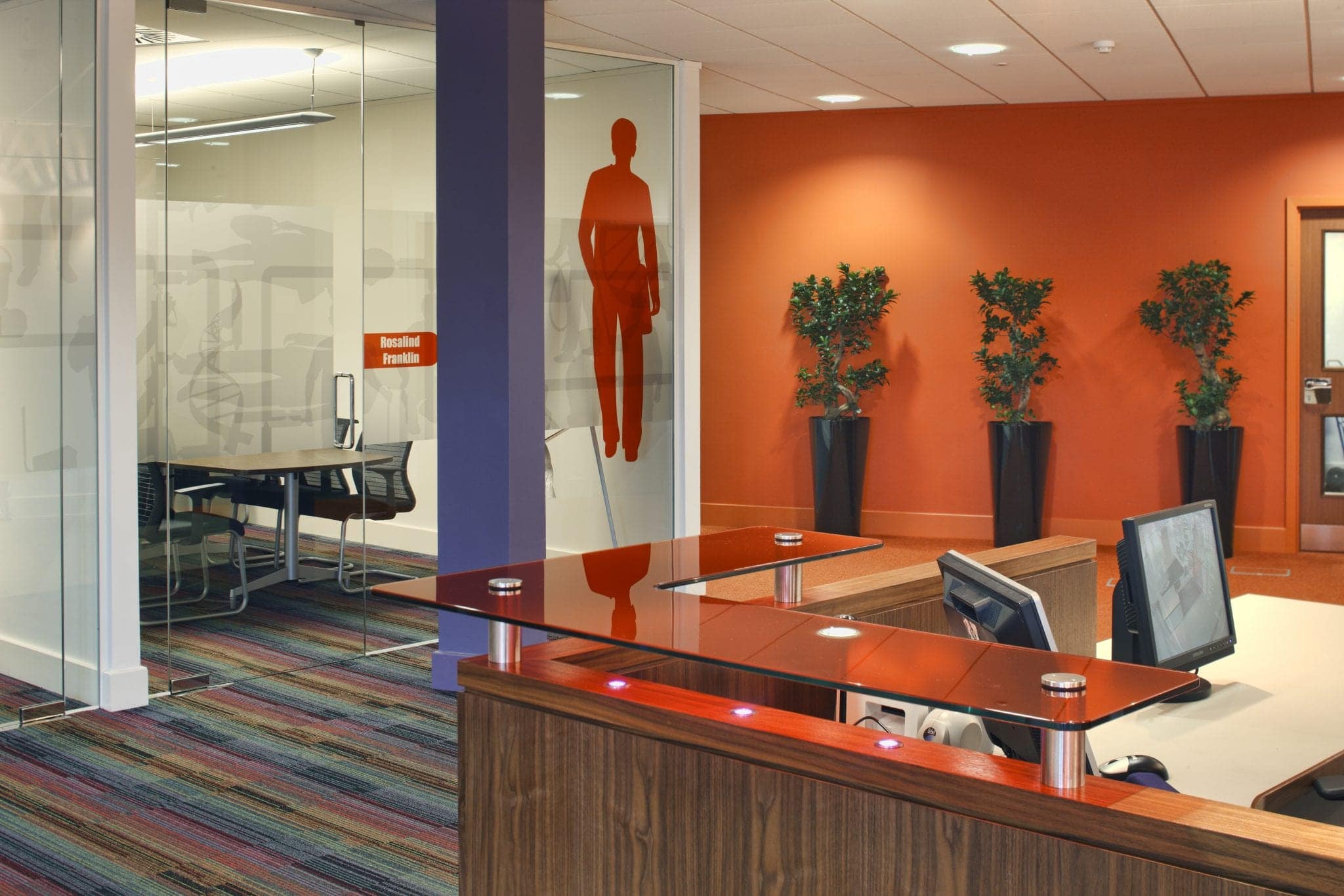 Workspace with orange human-figure wall graphics at Balfour Beatty Workplace, Bristol