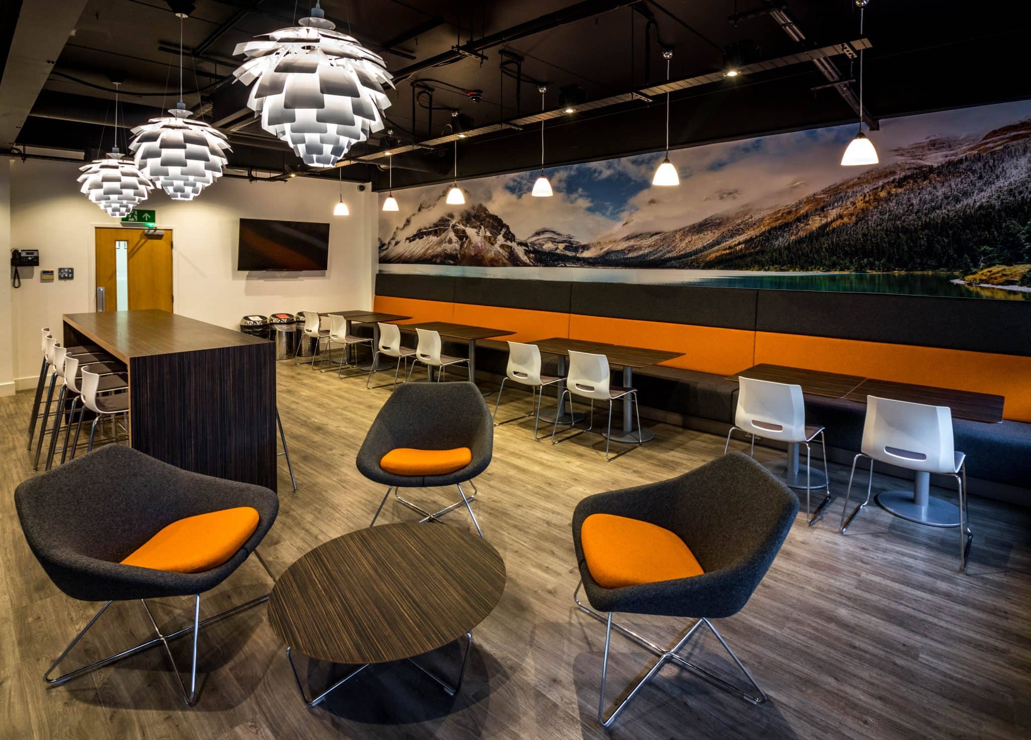 Staff canteen with exposed services and a long bench seat at South West Communications, Exeter