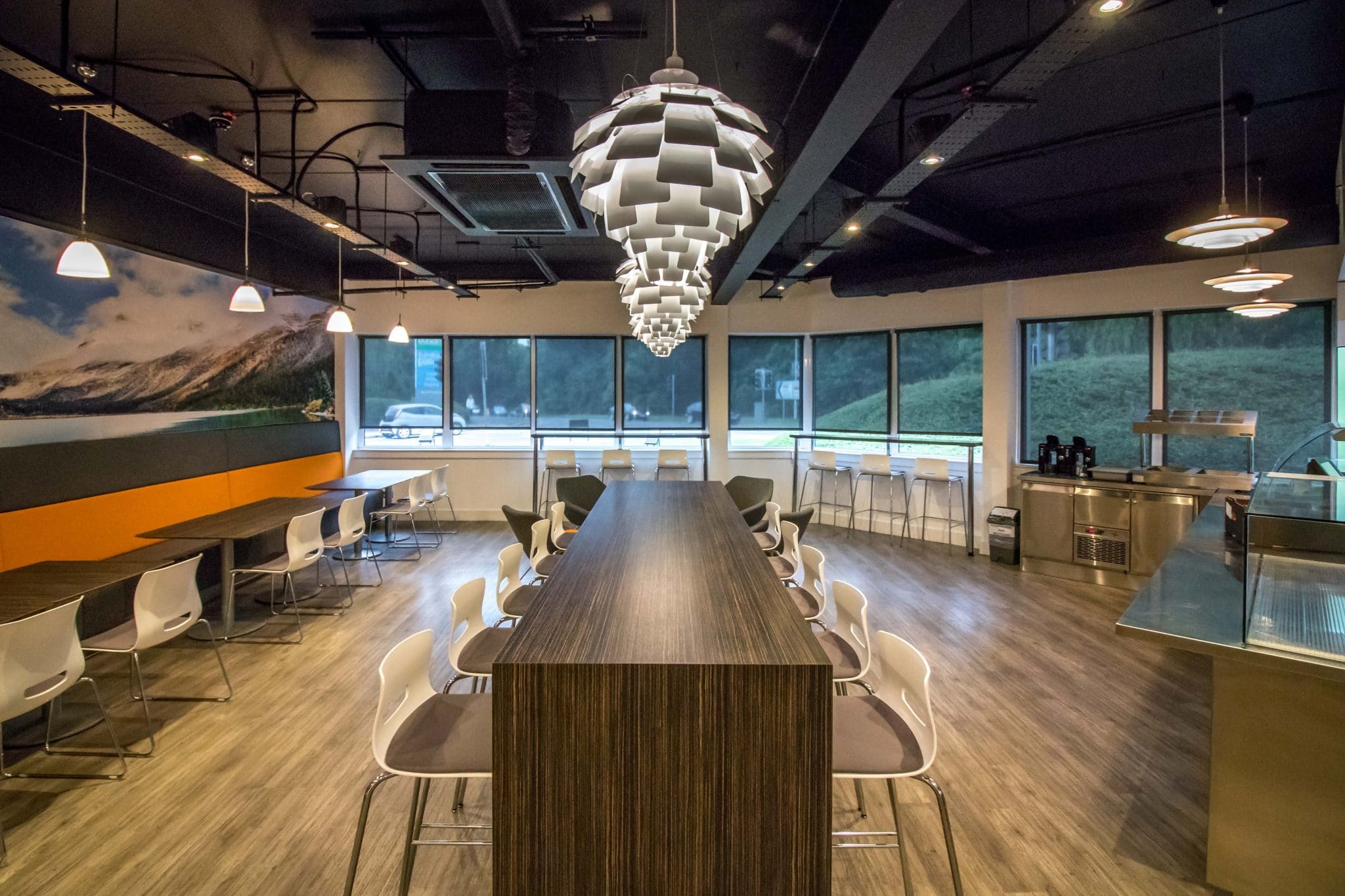 Canteen with long tables under exposed services at South West Communications, Exeter